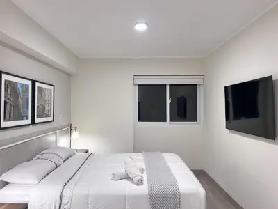 a white bedroom with a large bed with two pillows at Peruvian Apartments Miraflores in Lima