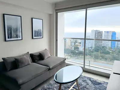a living room with a couch and a large window at Peruvian Apartments Barranco 2004 in Lima