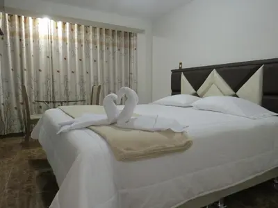 two swansrendered to look like hearts sitting on a bed at Hospedaje EL RINCONCITO II - Cerca al Aeropuerto Jauja in Jauja
