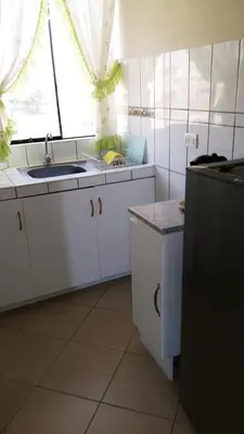 a kitchen with white cabinets and a sink and a window at Sol de Paracas Apart Hotel Pisco in Pisco