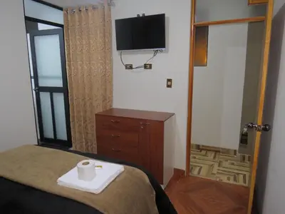 a bedroom with a bed and a tv on the wall at DEPARTAMENTO-Hospedaje EL RINCONCITO II 100m2, 3hab, 4baños, sala, comedor, cocina in Jauja