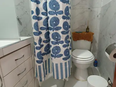 a bathroom with a toilet and a blue and white shower curtain at Acogedor APT a 20 min Aeropuerto in Lima