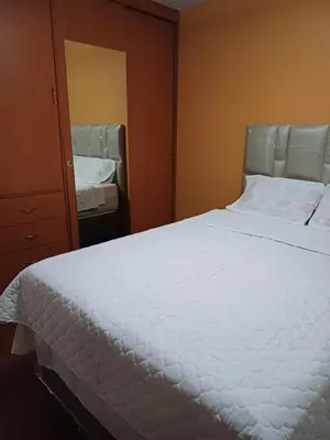 a bedroom with a large white bed and a mirror at Habitación acogedora Orué in Lima