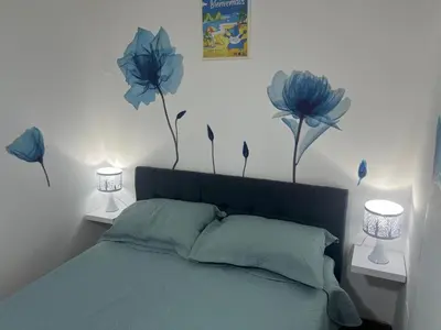 a bedroom with a bed with blue flowers on the wall at San Miguel, lindo depa, 3 camas, internet y cable in Lima