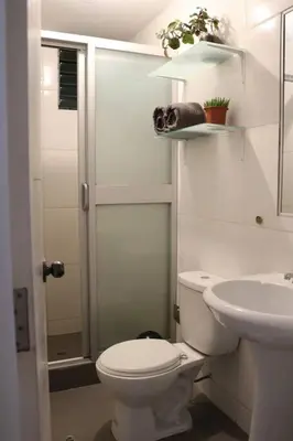 a white bathroom with a toilet and a sink at El colibrí de San Blas in Cusco