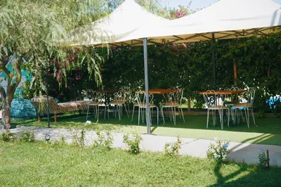 a group of tables and chairs under a white umbrella at Serenity Lodge in Ica