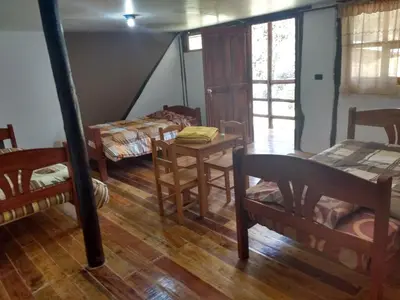 a room with two beds and a table and chairs at CasaNostra Choquequirao in Cachora