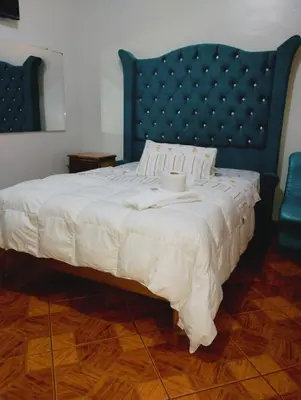 a bedroom with a large bed with a blue headboard at Hospedaje TOSCANO SUITES in Huancayo