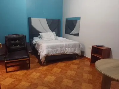a bedroom with a bed and a chair and a table at Hospedaje TOSCANO SUITES in Huancayo
