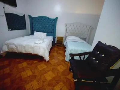 a bedroom with two beds and a chair at Hospedaje TOSCANO SUITES in Huancayo