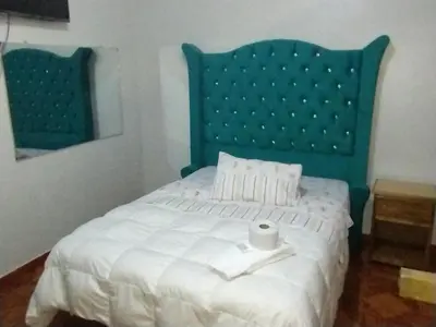 a bedroom with a bed with a green headboard at Hospedaje TOSCANO SUITES in Huancayo