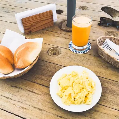 a table with a plate of food and a glass of orange juice at Kauhuhu Casa Hotel in San Bartolo