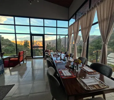 a dining room with a long table and chairs and windows at MISKI SAMAY DOMO BOUTIQUE in Urubamba
