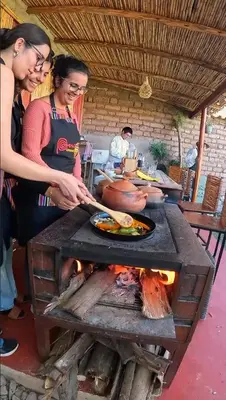 two women cooking food on a grill in a kitchen at MISKI SAMAY DOMO BOUTIQUE in Urubamba