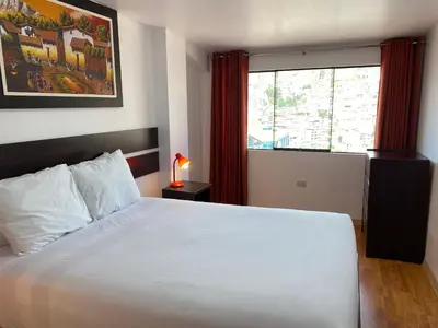a bedroom with a large white bed and a window at Adriano's Deluxe Apartments 3 in Cusco