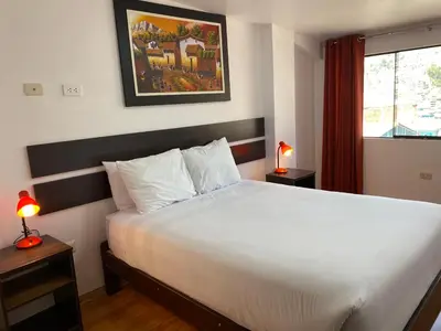a bedroom with a large white bed and a window at Adriano's Deluxe Apartments 3 in Cusco