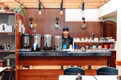 a man standing behind a counter in a coffee shop at Qosqo Wasi in Cusco