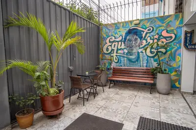 a patio with a bench and a wall with a mural at Magdalen House in Lima