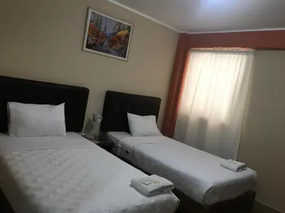 two beds in a hotel room with a window at CARDOS HOSTAL in Pisco