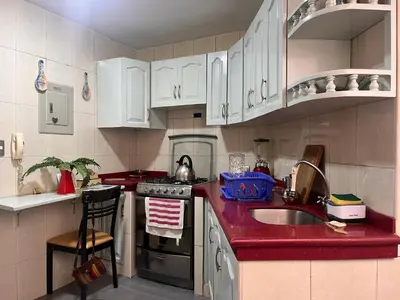 a kitchen with white cabinets and a red counter top at Céntrico y funcional apartamento 2 dormitorios JESÚS MARÍA LIMA in Lima