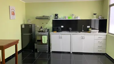 a kitchen with white cabinets and a black refrigerator at Lindo depa san miguel, 3camas, wifi, terraza. in Lima