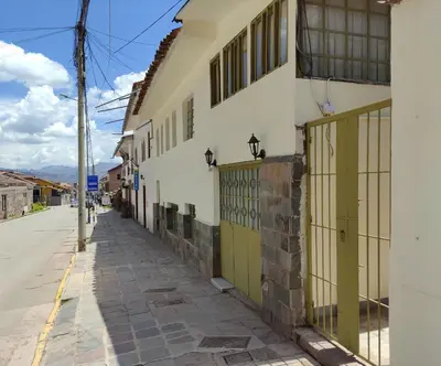 a street with a white building with green doors at Centro Cusco Inti Saphy in Cusco