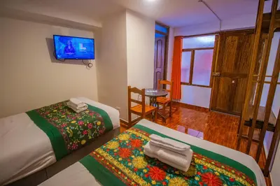 a room with two beds and a television and a table at Munay Ñusta Cusco in Cusco