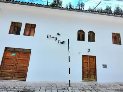 a white building with two doors and the words his happy music at Munay Ñusta Cusco in Cusco