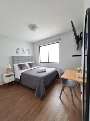 a bedroom with a bed and a table and a desk at Miraflores - Dormitorio en Departamento compartido Baño Exclusivo Externo in Lima
