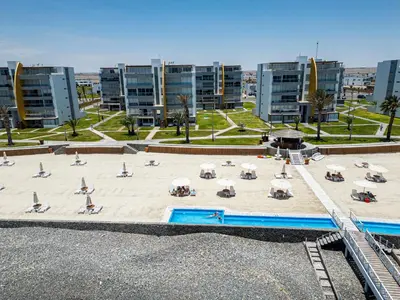 a large beach with chairs and umbrellas and buildings at Sotavento Oceanfront Condos by Vibrant in Paracas