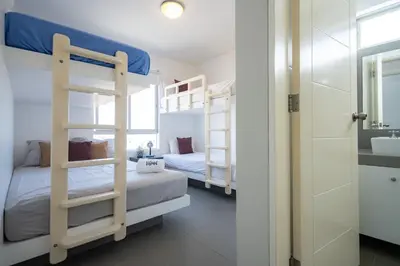 a bedroom with two bunk beds and a bathroom at Sotavento Oceanfront Condos by Vibrant in Paracas