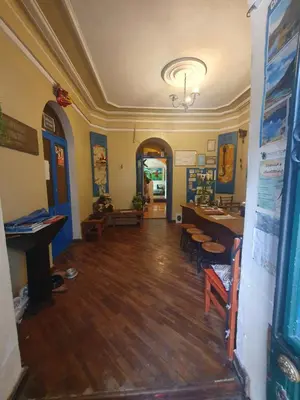 a room with a wooden floor and a table and chairs at Royal Frankenstein Hostel in Cusco