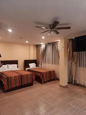a bedroom with two beds and a flat screen tv at BRISAS DE LA BAHIA HOTEL in Paracas
