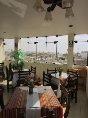 a restaurant with tables and chairs and large windows at BRISAS DE LA BAHIA HOTEL in Paracas