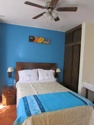 a blue bedroom with a bed with a ceiling fan at BRISAS DE LA BAHIA HOTEL in Paracas