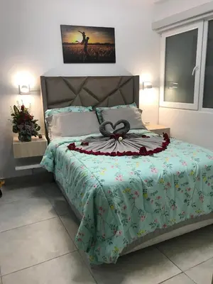 a bed with a green comforter with a bow on it at Albano habitación acústica cocina y baño in Chosica