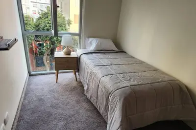 a bedroom with a bed with a nightstand and a window at Amazing 3BR in Miraflores in Lima