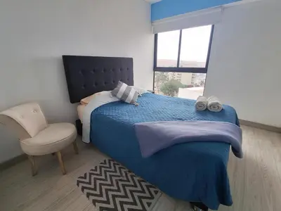 a bedroom with a bed and a chair and a window at Apartamento con increíble vista al mar in Lima