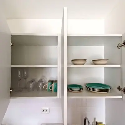 a kitchen with white shelves with plates and bowls at Apartamento con increíble vista al mar in Lima