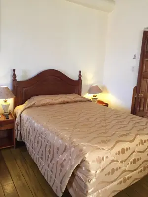a bed in a bedroom with two night stands and two lamps at Hotel Midori in Cusco