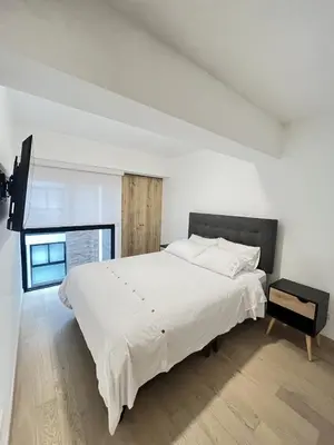 a white bedroom with a large bed and a window at Departamento de Estreno en Miraflores in Lima