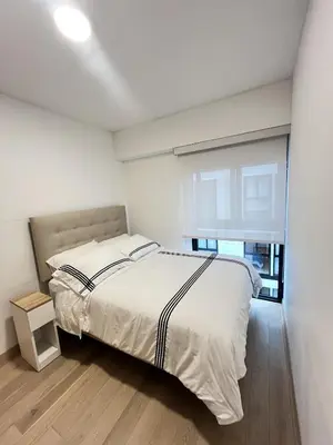 a white bedroom with a bed and a window at Departamento de Estreno en Miraflores in Lima
