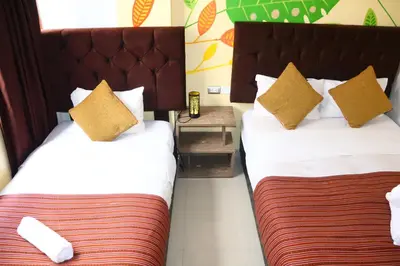 two beds in a hotel room with yellow pillows at MACHUPICCHUROYAL B y B in Machu Picchu