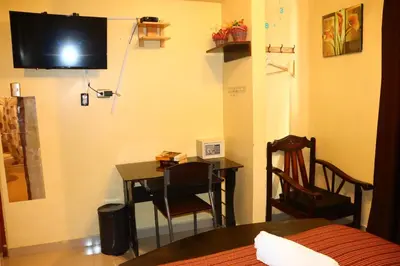 a room with a desk and a television on the wall at MACHUPICCHUROYAL B y B in Machu Picchu