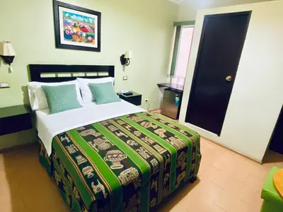a bedroom with a bed with a green and white comforter at Hotel Tinkus Inn in Lima