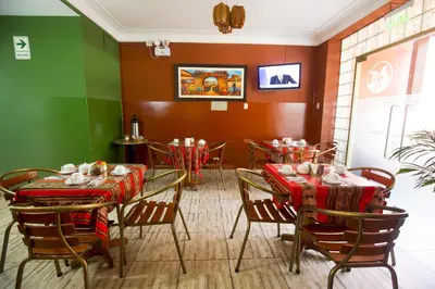 a restaurant with tables and chairs with red and green walls at Hotel Tinkus Inn in Lima