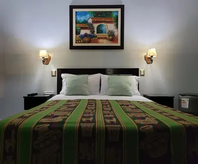 a bedroom with a large bed with a colorful blanket at Hotel Tinkus Inn in Lima