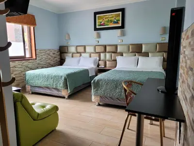 a hotel room with two beds and a chair at Hotel Tinkus Inn in Lima