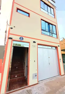 a building with two garage doors and a staircase at Mini Hostal Cardos in Pisco