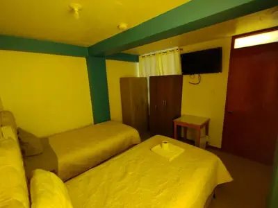 a room with two beds and a tv on the wall at hotel plaza chinchero in Cusco